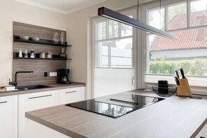 Une cuisine moderne équipée d’une cuisinière intégrée, d’une machine à café et d’une fenêtre donnant sur une maison.