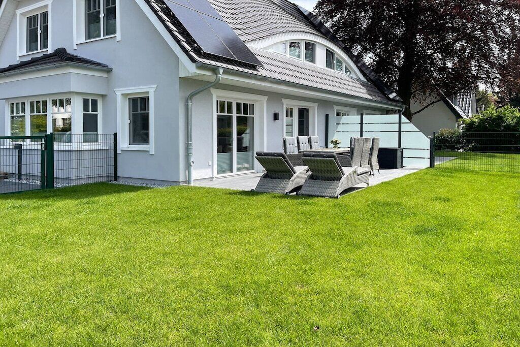 A modern house with a sloped roof, large windows, and a well-maintained lawn.