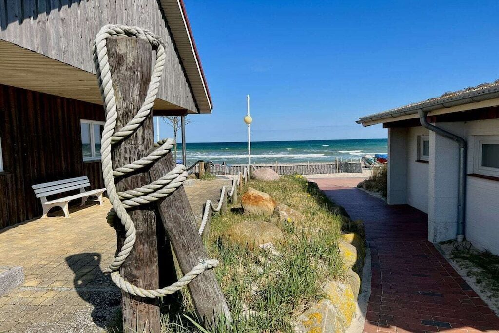A wooden building with a rope feature, a bench, and a pathway leading to the beach.