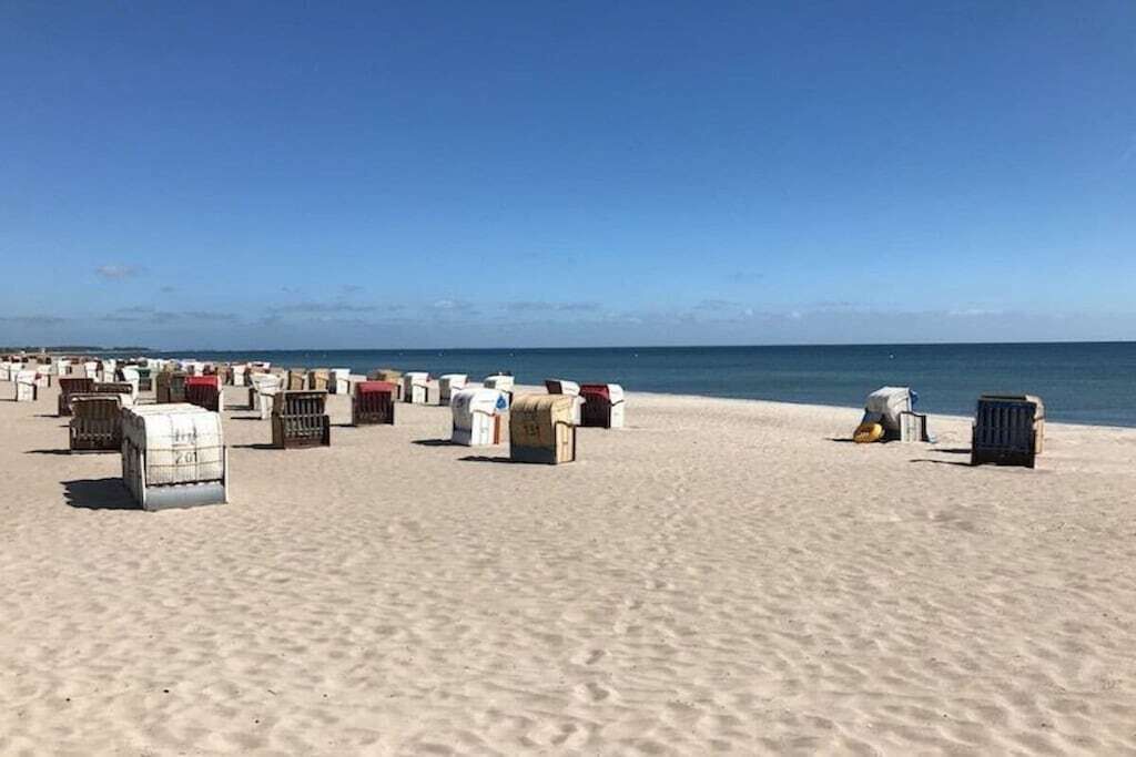 Una playa con numerosos contenedores blancos y rojos dispersos sobre la arena.