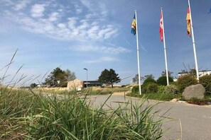 A paved pathway leading to a building with multiple flags. - Holiday apartment in Dahme with swimming pool (Dahme)