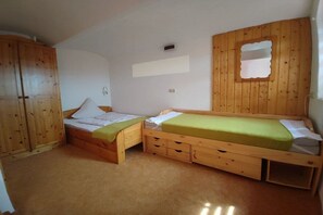 Ein Zimmer mit zwei Holzbett, einem Kleiderschrank und einem kleinen Fenster.