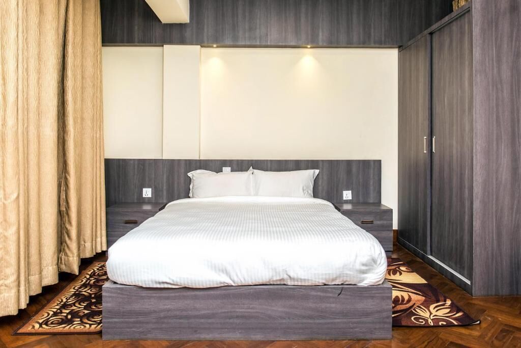 Quarto com cama, cortinas, tapete estampado e guarda-roupa.