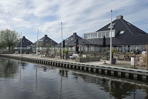 A waterfront property with a row of houses, a dock, and outdoor seating areas. - ||----------houseBoat Tranquility------|| (Offingawier)