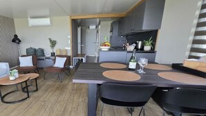 A modern dining area with a long table, black chairs, and a kitchen in the background.
