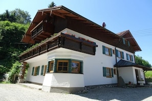 A traditional chalet-style building with a sloped roof, wooden balconies, and a stone foundation. - Villa in the woods - Eagle's nest (Roßhaupten)