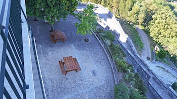 A courtyard with a paved area, two wooden benches, and a small tree.