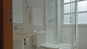 Un baño con inodoro, lavamanos y cabina de ducha de vidrio.