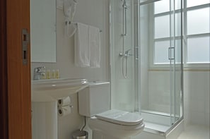 A bathroom with a toilet, sink, and glass shower enclosure. - Casa São Bernardo de Claraval (Terras de Bouro)