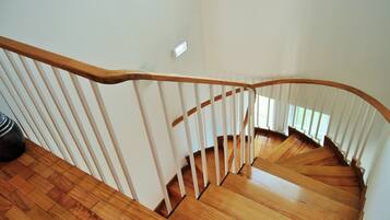 A wooden staircase with white balusters and a handrail, leading to an upper floor.