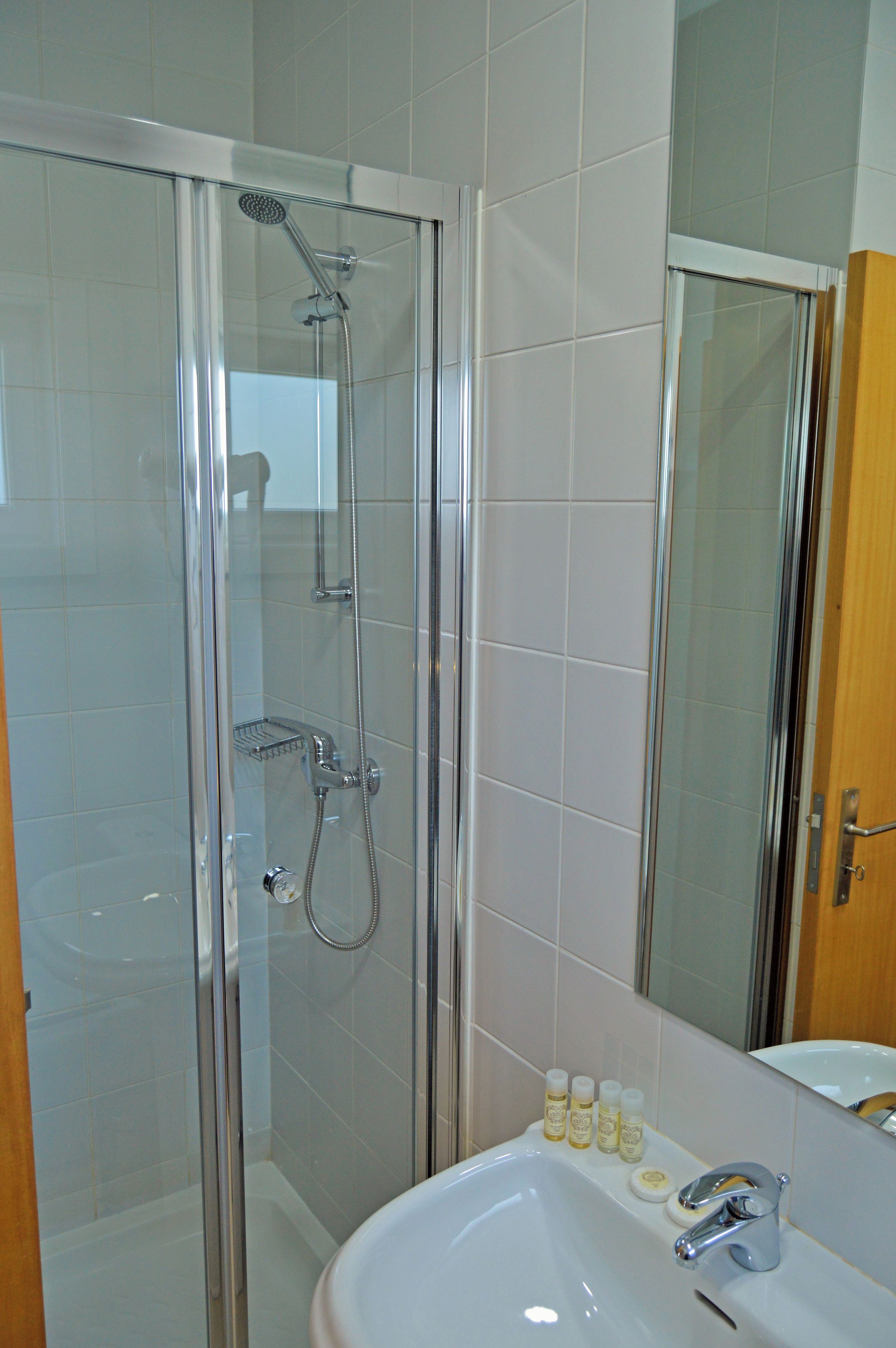 Un baño moderno con ducha envuelta en vidrio, un lavabo blanco y un espejo.