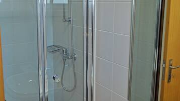 Un baño moderno con ducha envuelta en vidrio, un lavabo blanco y un espejo.