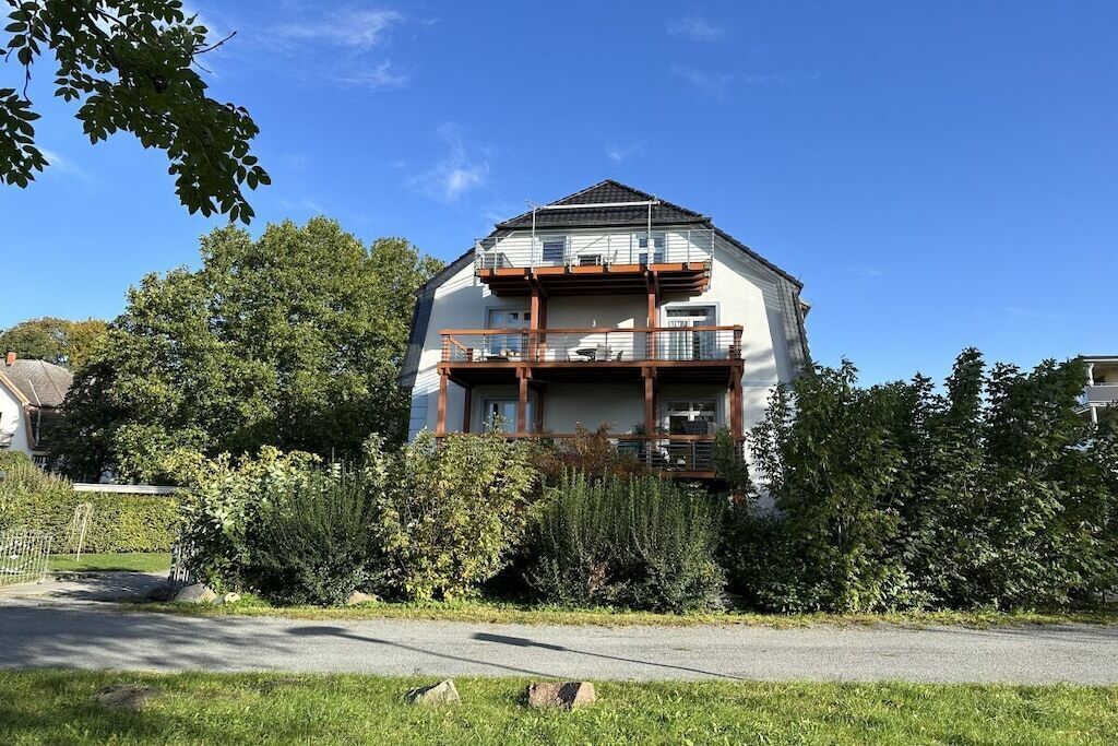 Ein zweigeschossiges Wohngebäude mit einem Balkon im oberen Stockwerk.