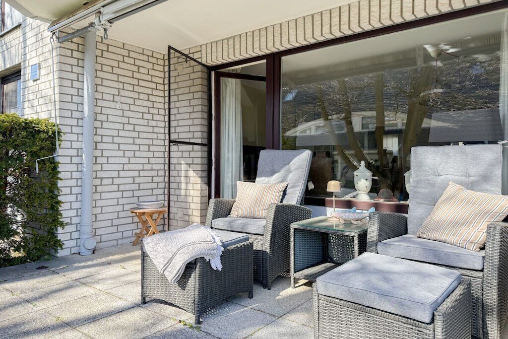An outdoor seating area with wicker furniture and a glass door leading to a room.