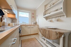 Een compacte keuken met een houten aanrechtblad, witte kastjes en een raam dat voor natuurlijk licht zorgt.