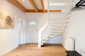 A staircase with white railings and wooden steps leading to a door with a glass panel. - Holiday home with 3 bedrooms (Timmendorfer Strand\/Niendorf)