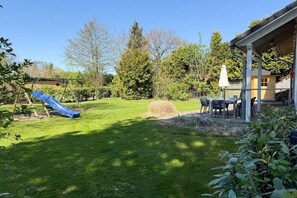 A backyard with a slide, a covered patio area, and a hay bale. - Holiday home with 3 bedrooms (Timmendorfer Strand\/Niendorf)