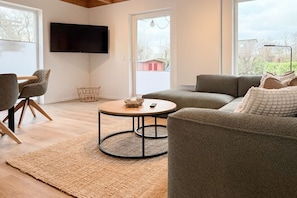 A living room with a sofa, a coffee table, and a TV. - Holiday home with 3 bedrooms (Timmendorfer Strand\/Niendorf)