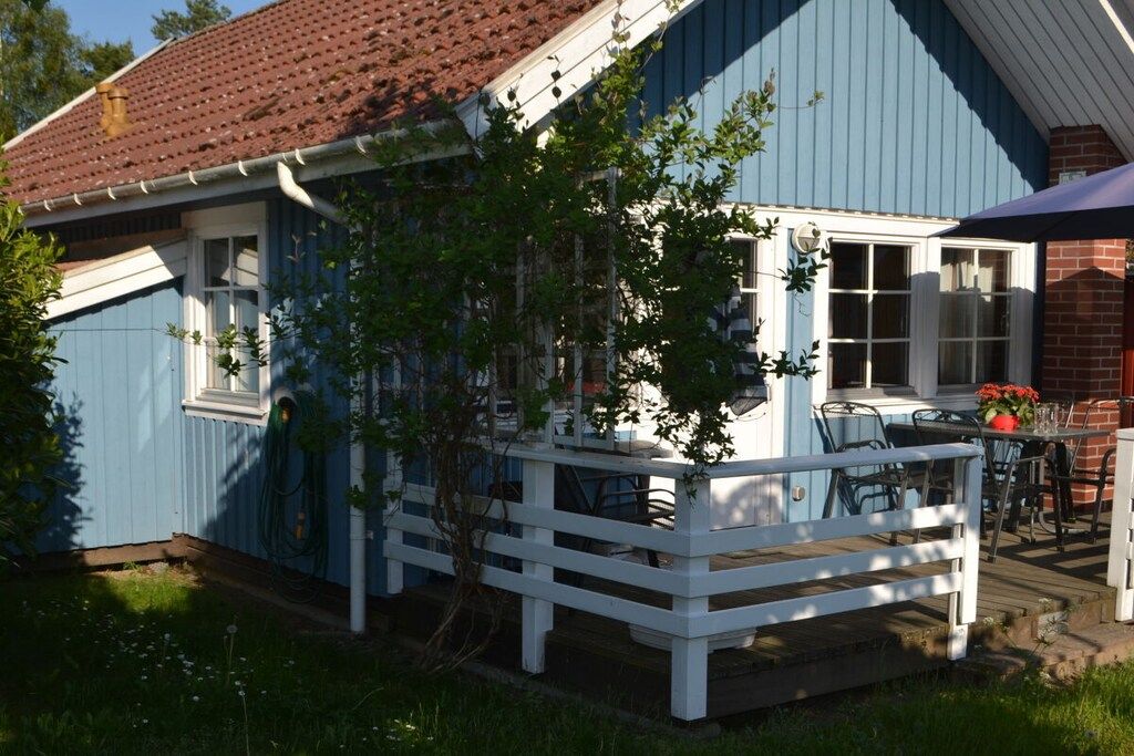 A blue house with a white porch and a brick chimney.