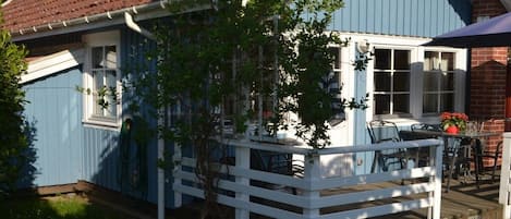 A blue house with a white porch and a brick chimney.
