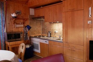 Eine kleine Küche mit Holzschränken, einer Mikrowelle, einem Herd und einem Spülbecken.