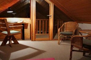 Ein gemütliches Dachzimmer mit einem Holztisch, Stühlen und einem kleinen Tisch.