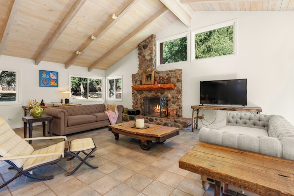 A spacious living room with a stone fireplace, a television, and comfortable seating. - Rancho de los Venados (Santa Ynez)