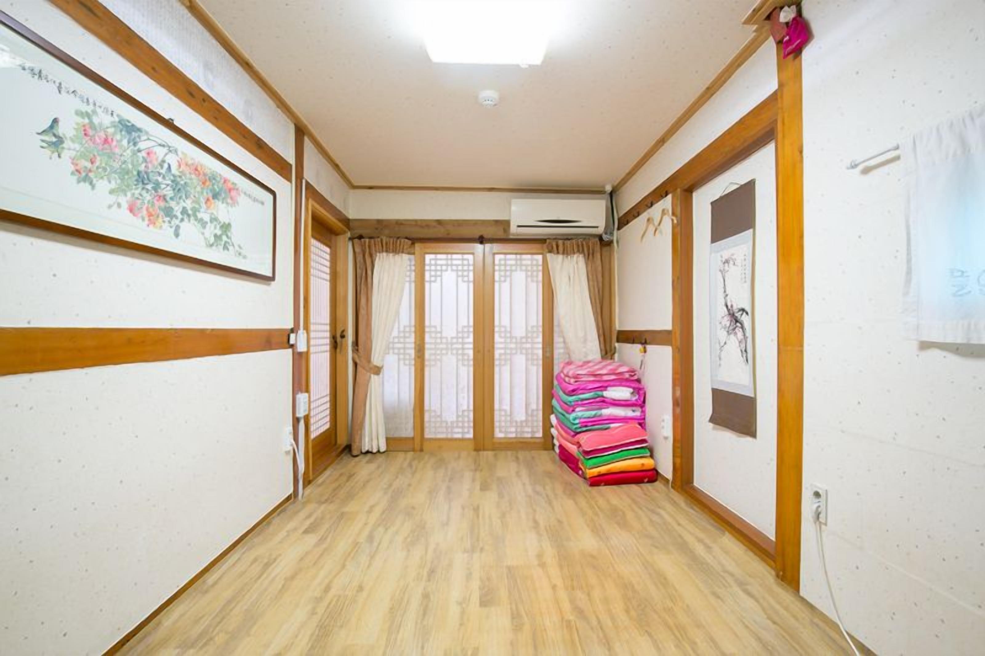 Un pasillo con piso de madera, una pila de toallas coloridas y una puerta corredera japonesa tradicional.
