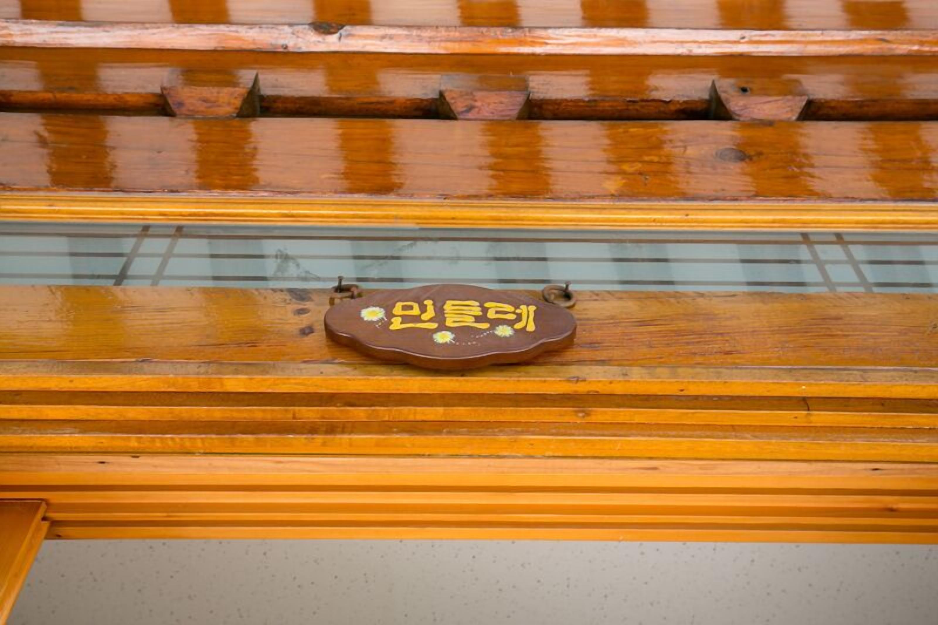 Techo de madera con un soporte metálico y una placa marrón con texto amarillo.