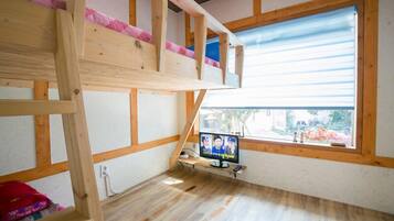 A room with a bunk bed, a television, and a window with a view.