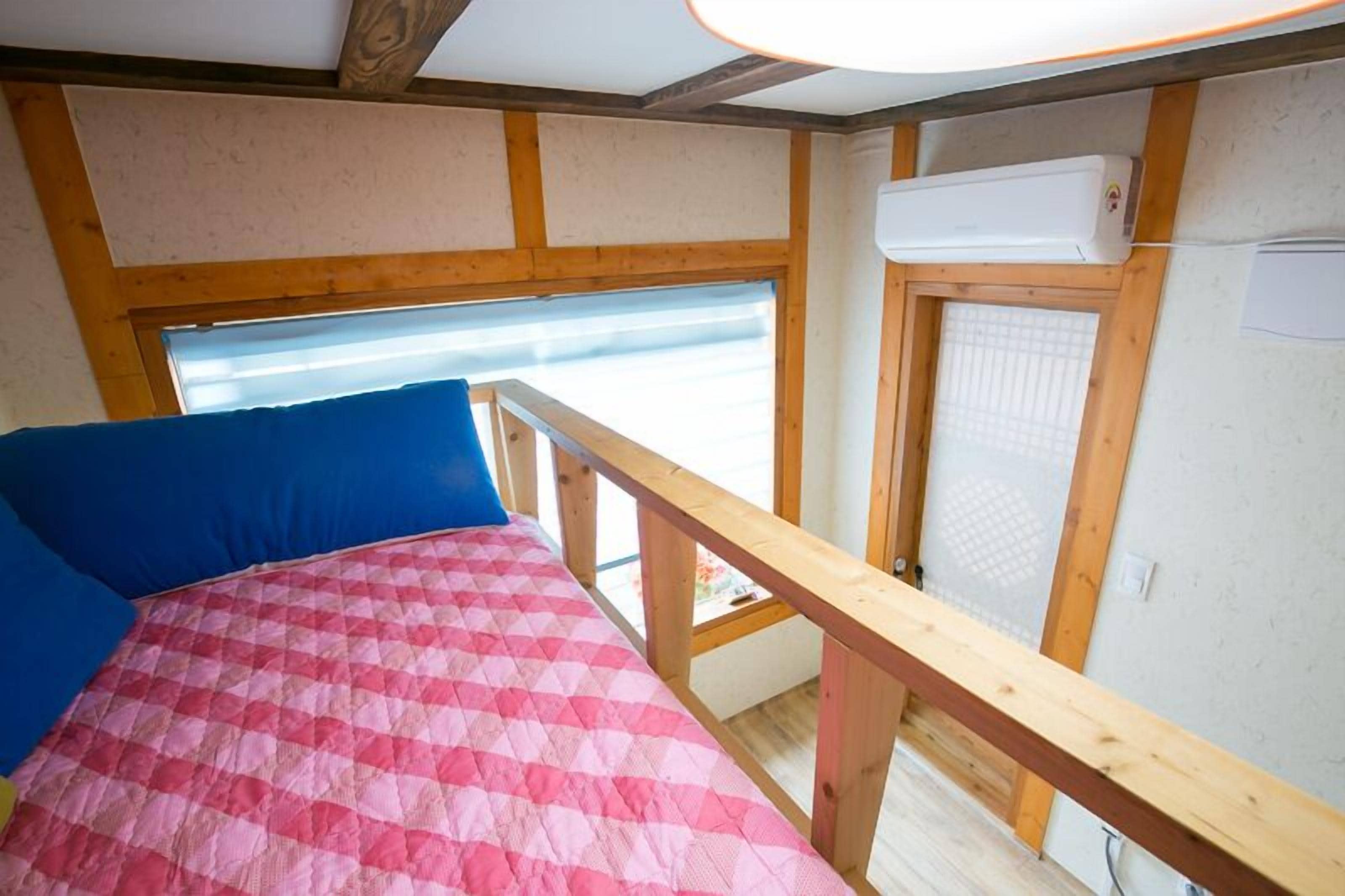 Una habitación con cama, ventana y aire acondicionado.