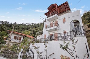 Un edificio de dos pisos con un balcón, una escalera y vistas a un paisaje montañoso.