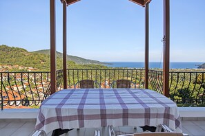 Una mesa colocada en un balcón con vista a un paisaje costero.