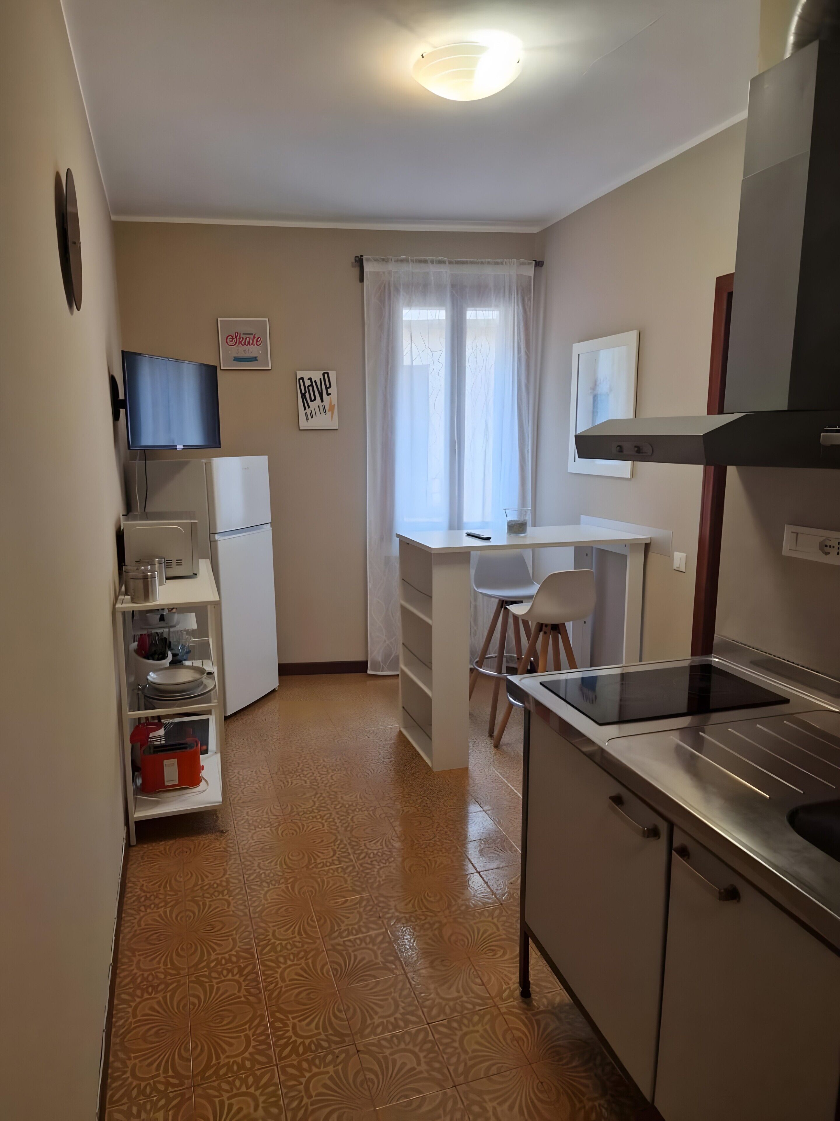 Una cucina compatta con frigorifero, piano cottura e un'area pranzo con sedia e tavolo.