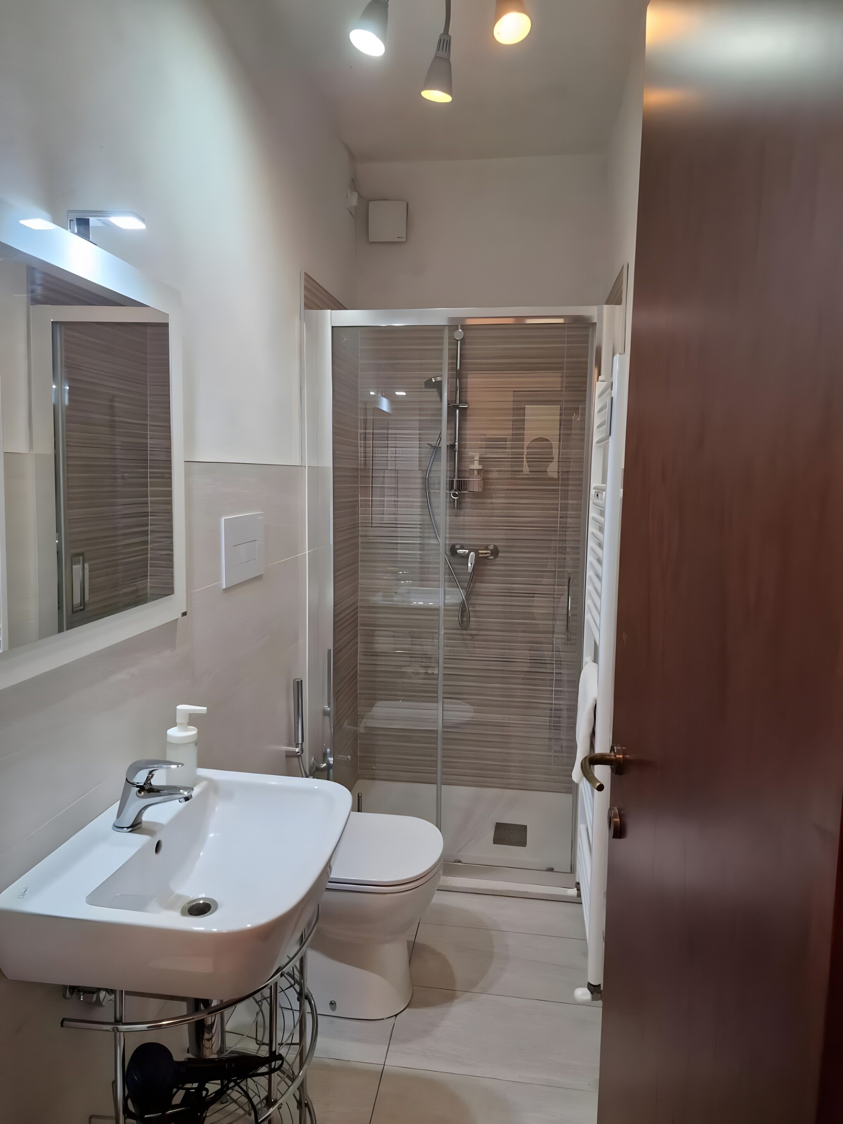 Un bagno con un lavandino bianco, un water e una cabina doccia in vetro.