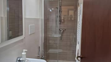 Un bagno con un lavandino bianco, un water e una cabina doccia in vetro.