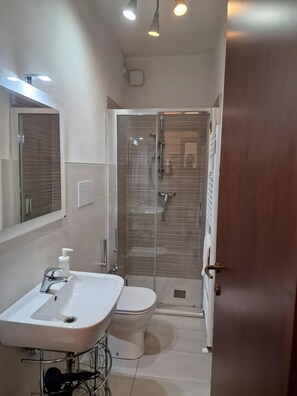 Un bagno con un lavandino bianco, un water e una cabina doccia in vetro.