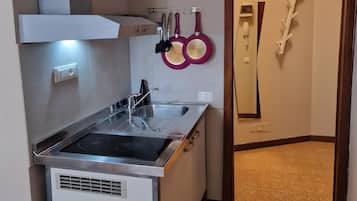 Una cucina compatta con piano cottura integrato, lavello e cappa aspirante.