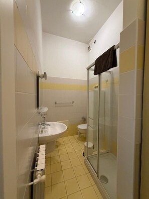 Un baño pequeño con lavamanos, inodoro y cabina de ducha de vidrio.