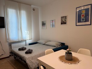 Un dormitorio con una cama, una mesa con un jarrón y detalles decorativos en la pared.