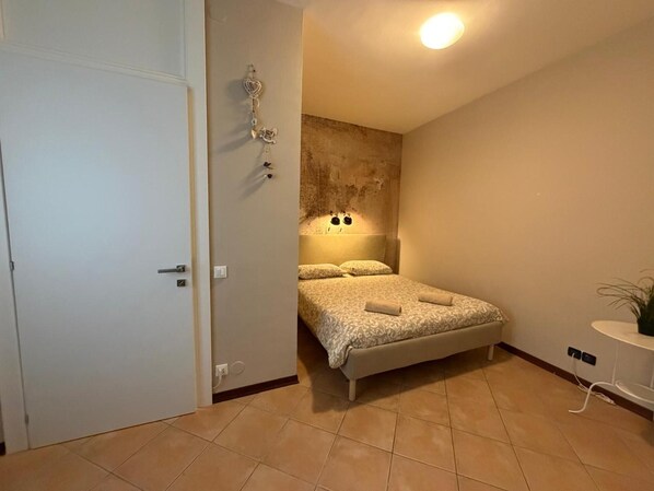 Un dormitorio con una cama, una lámpara de pared y una puerta.