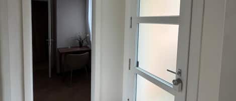 Un pasillo con una puerta blanca, un comedor y un equipo de aire acondicionado montado en la pared.