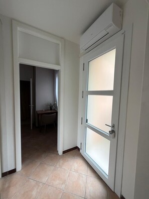 A hallway with a white door, a dining area, and an air conditioning unit mounted on the wall. - Apartment 'Andreini20' with Wi-Fi and Air Conditioning (Padua)