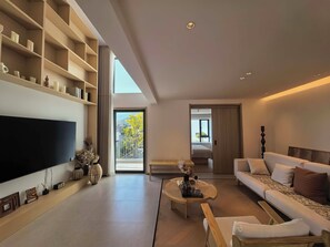 A modern living room with a flat-screen TV, a sofa, a coffee table, and a bookshelf. - SYCX Retreat Villas (Dali)