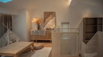 A modern interior with a wooden table, a vase with dried flowers, a patterned throw, and a large abstract painting.