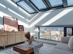 A modern living room with a skylight, a large window, and a city view. - SYCX Retreat Villas (Dali)