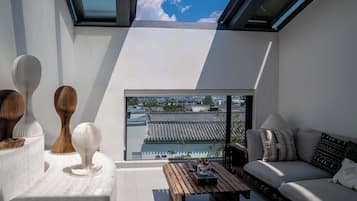 Una sala de estar moderna con vistas a edificios tradicionales, un sofá, una mesa de centro y esculturas decorativas.