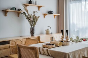 Un comedor con una mesa de madera, sillas y un florero con flores secas.