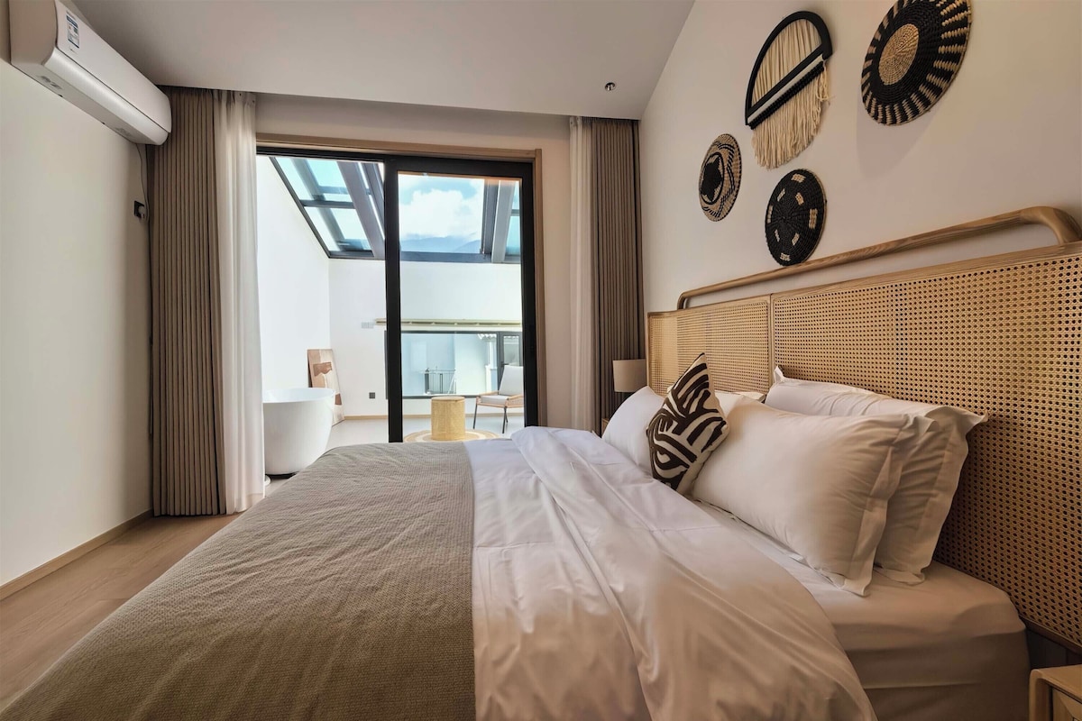 Quarto de hotel com uma cama grande, varanda e vista, e um ventilador de teto.