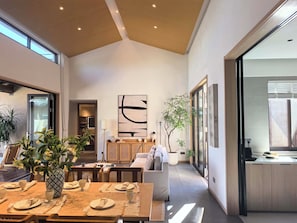 Ampla sala de estar com mesa de jantar posta para quatro pessoas, sofá e uma grande pintura abstrata na parede.